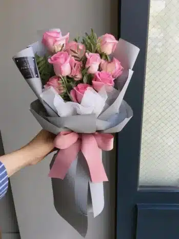 Mostrar la sofisticación y el cuidado en la presentación del ramo, destacando el papel importado, el moño de satín y la tarjeta personalizada, para atraer a clientes que buscan un regalo especial.