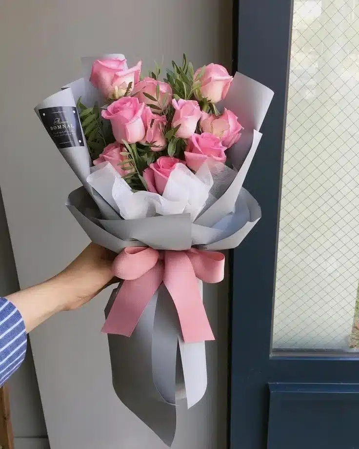Mostrar la sofisticación y el cuidado en la presentación del ramo, destacando el papel importado, el moño de satín y la tarjeta personalizada, para atraer a clientes que buscan un regalo especial.
