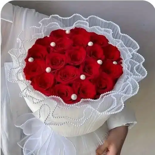 Manual elegante de rosas rojas envuelto en organza con perlas y el mensaje ¡Feliz Día Mamá! floristería exotic flowers domicilio en bucaramanga y área metropolitana.