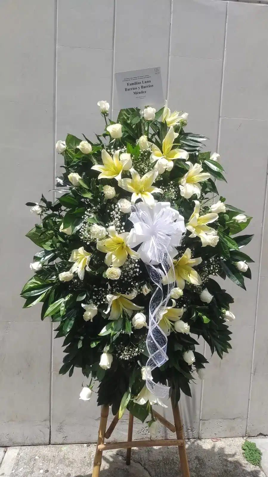 Arreglo floral para condolencias con lirios y follajes verdes de Exotic Flowers Bucaramanga, ideal para ceremonias conmemorativas.